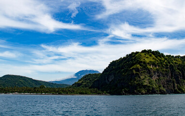 View of Agun volcano and mountains against the blue sky with clouds from Gili island, Indonesia