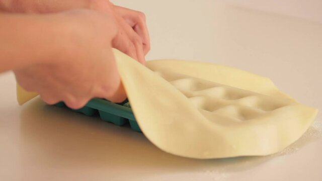 preparing ricotta cheese ravioli pasta in a plastic ice cube trays with a tart dough