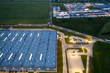 Night Aerial view of goods warehouse. Logistics center in industrial city zone from above. Aerial view of trucks loading at logistic center