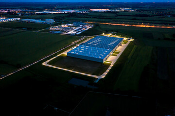 Fototapeta na wymiar Night Aerial view of goods warehouse. Logistics center in industrial city zone from above. Aerial view of trucks loading at logistic center. View from drone.