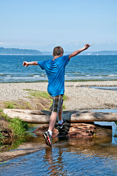 This 13 Year Old Caucasian Boy Is Running And Jumping While Playing At The Beach.  His Arms Are Held High In The Air, Ready To Conquer The World.  Full Body, Rear View In Vertical Format.