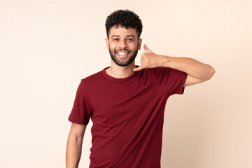 Young Moroccan man isolated on beige background making phone gesture. Call me back sign