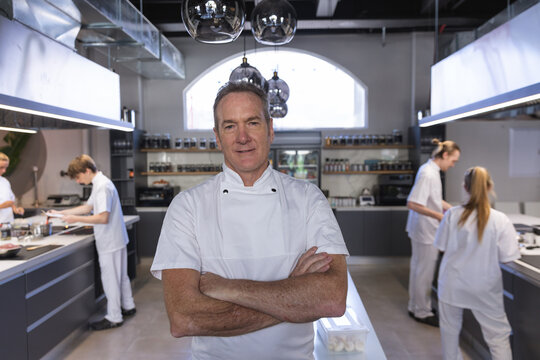 Portrait of senior male chef standing with his arms crossed at restaurant kitchen