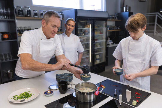Senior male chef teaching cooking to young male chef at restaurant kitchen