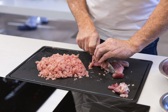 Mid section of chef cutting meat at restaurant kitchen
