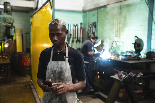 Black African American Male factory wearing apron using smartphone at the factory