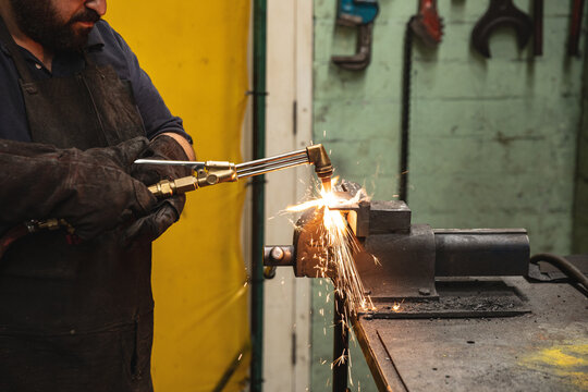 Male factory worker using welding torch at the factory