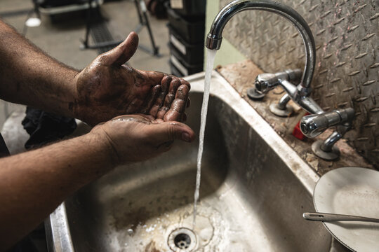 Close-up of a male factory worker washing hands in the sink