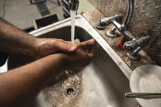 Close-up of a male factory worker washing hands in the sink