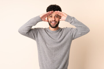 Obraz premium Young Moroccan man isolated on beige background with surprise expression