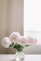 Beautiful pink peonies in a vase at home interior. Flower composition. Floral shop concept. Beautiful fresh cut bouquet. copyspace