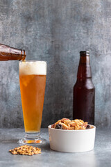 Pouring beer from bottle in glass on gray backgroung