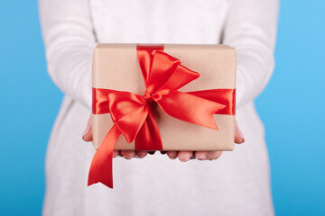 Present box with red ribbon in hand.