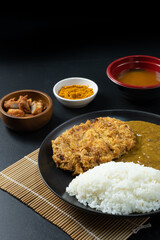 Tonkatsu Curry Rice (Japanese deep-fried pork cutlet with Curry rice) served with karaage (Japanese style fried chicken). on black background.