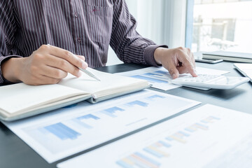 The hands of a male businessman are analyzing and calculating the annual income and expenses in a...