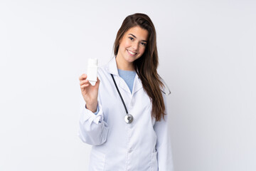 Teenager girl over isolated white background wearing a doctor gown and holding pills