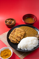 Tonkatsu Curry Rice (Japanese deep-fried pork cutlet with Curry rice) served with karaage (Japanese style fried chicken). on red background. 