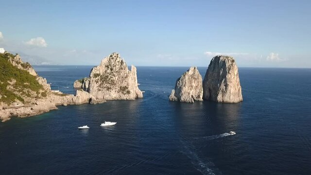 Drone Capri symbol Faraglioni di Mezzo cliffs in the blue sea with boats