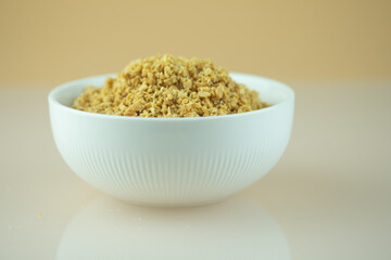 Bowl of roasted crushed peanuts on white background.