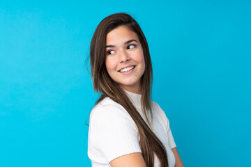 Fototapeta premium Teenager girl over isolated blue background with arms crossed and happy