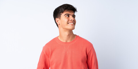 Handsome man over isolated blue background thinking an idea while looking up