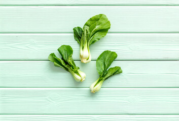 Bok choy on green wooden background top-down