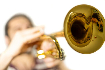 Trumpet player, plays the instrument, trumpet is in focus, musician is out of focus / isolated white background