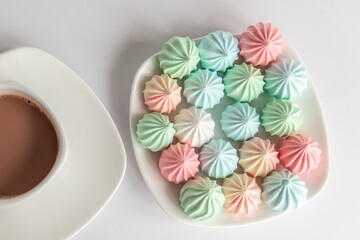 Multicolored meringues and a cup of coffee on a white background. isolated
