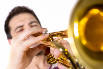 Trumpet player, plays the instrument, eyes are shut and blowing / Focus is on the trumpet buttons /...