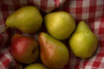 fresh yellow pears and red apples on checkered fabric