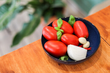 Fresh vegetables - ingredients in a bowl - tomatoes, basil, onion, garlic, chilly paper on a table