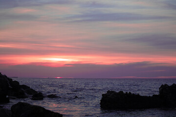 colorful yellow pink sunset on rocky beach with cloudy sky