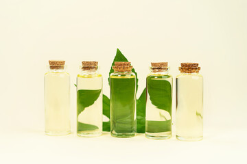 Glass bottles with herbal CBD oil, THC tincture and hemp leaf on pastel beige background.