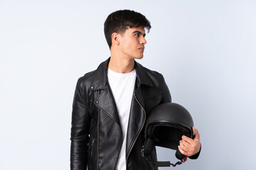 Man with a motorcycle helmet over isolated blue background looking side