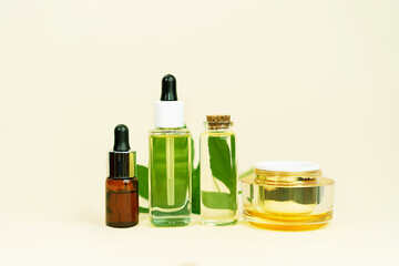 Various glass bottles with herbal CBD oil, THC tincture and hemp leaf on pastel beige background.