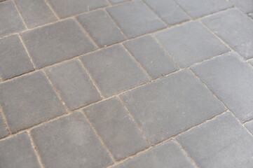 Gray pavement tiles in the street creating a regular grid and texture