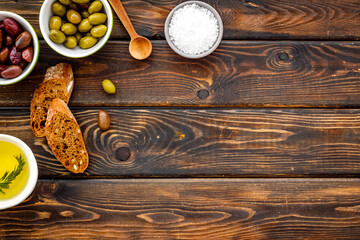 Top view of olives, olive oil, bread on wooden table top view copy space