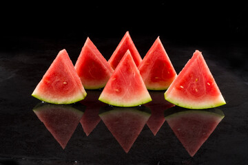 Pieces of watermelon in a black tray on a black background