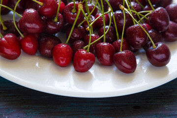 Fresh cherry on plate on wooden blue background.