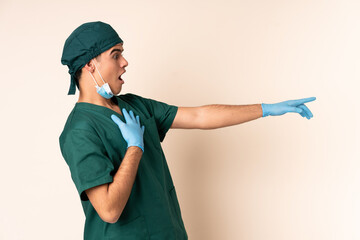 Surgeon man in blue uniform over isolated background pointing finger to the side