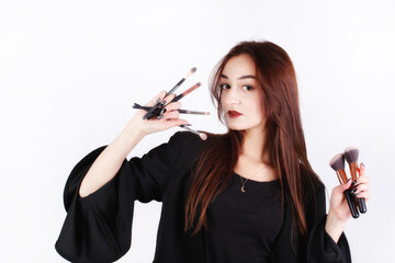 Beautiful woman with makeup brushes on white background