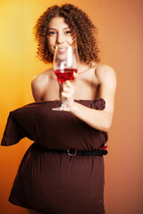 Beautiful woman with a glass of red wine and a pillow instead of a dress