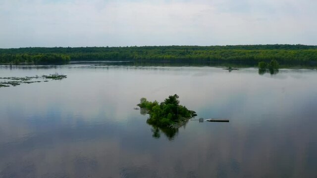 Aerial shot approaching and descending upon a small island in the middle of a lake