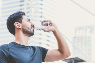 Young athletes man drinking mineral water after exercise.