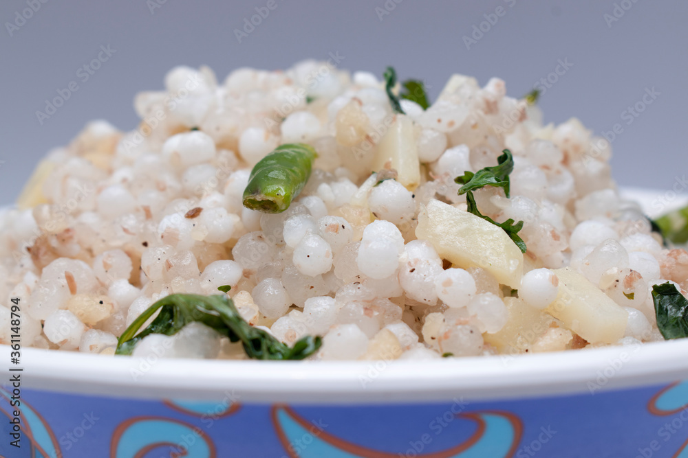 Wall mural close up shot of traditional maharashtrian dish ,sabudana khichdi in bowl with green chilly and vegetables on top