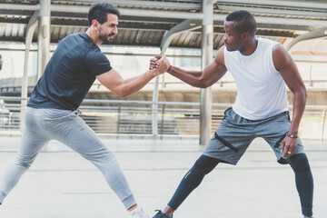 Fototapeta premium Two handsome muscular athletes men are doing a handshake pose to stretch before exercising.