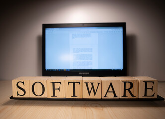 The laptop screen on the table is open. Software word on wooden cubes on laptop.