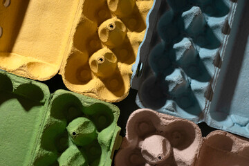 Multi-colored egg trays in hard light layout. The concept of collecting waste and transferring paper for recycling, preserving the environment and reducing the harm of ecology. Top view, flat lay.