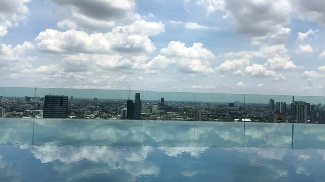 Rooftop infinity pool in city centre of Bangkok with passing clouds. Time-lapse