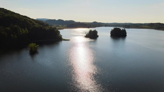 Aerial tilt reveal shot of the sun shining over a tranquil lake in Germany